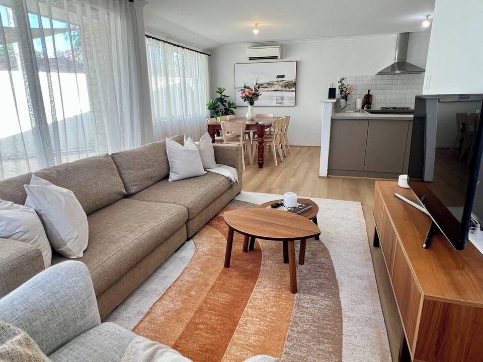 Relax in this open-plan living area featuring a large sofa, wide-screen TV, and an eight-seater dining table, all kept perfectly cool with air conditioning.