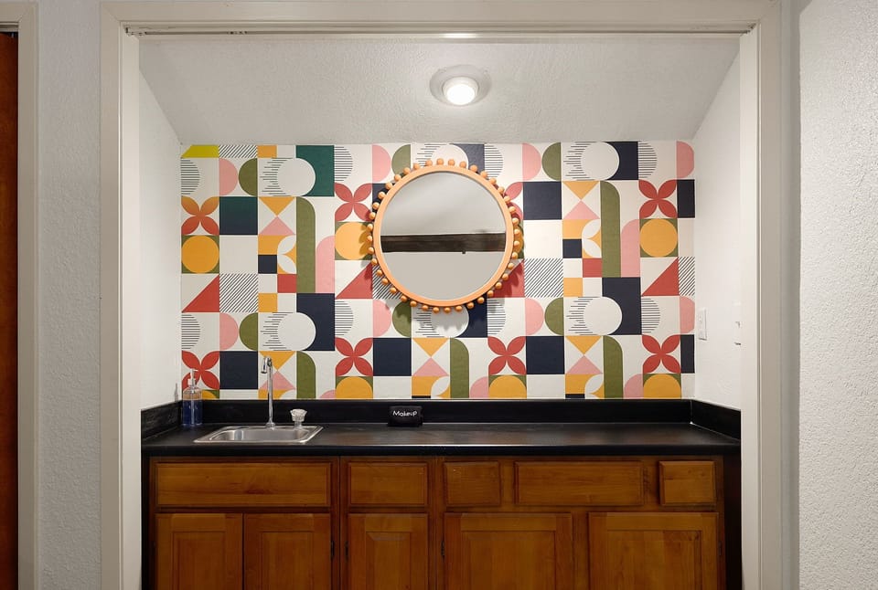 Convenient in-room vanity area with modern finishes and charming accent wall.