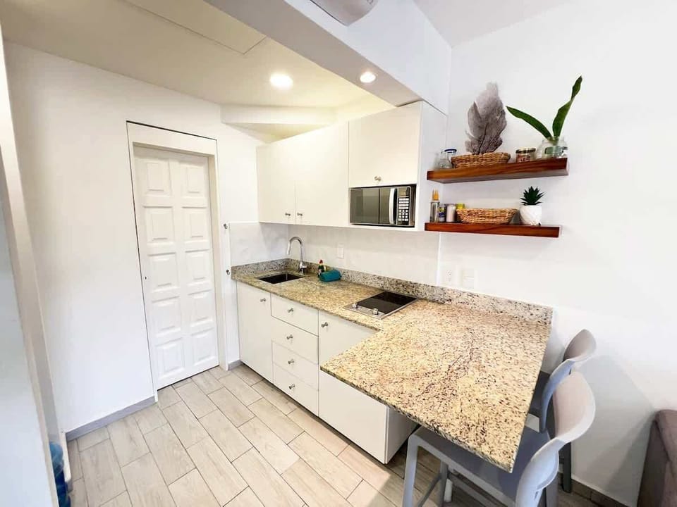 “Cocina completa con encimeras de granito, refrigerador, microondas y barra de desayunos. Todo lo que necesitas para estancias largas o cortas.”