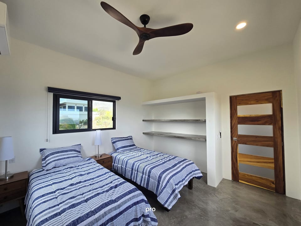 Twin size bed set up with custom wood ceiling fan and door. AC in each bedroom.