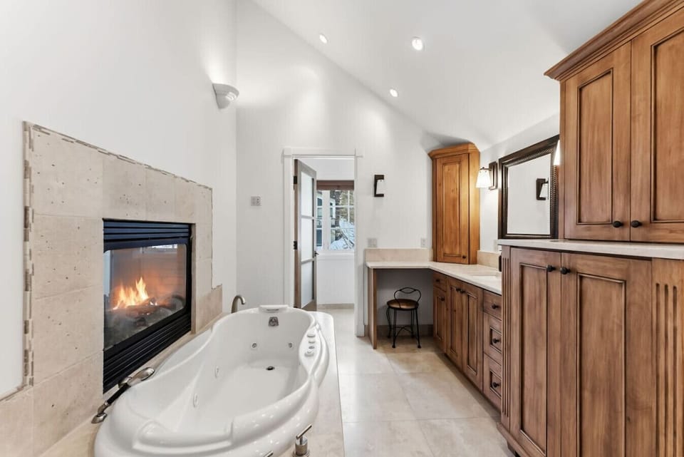 Primary bedroom with king bed, double sided fireplace, smart TV, and spa-like en suite bathroom