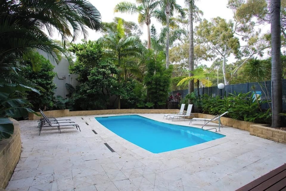 Sunny Retreat: Dive into relaxation with a sparkling pool surrounded by lush tropical greenery!