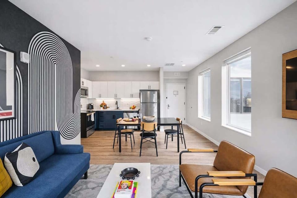 Bright open floor living space featuring a smart flat-screen TV and designer furnishings. Connects to the dining area and kitchen.