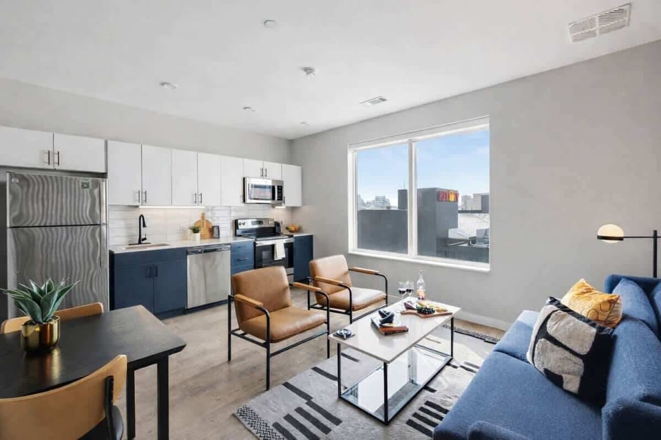 Bright open floor living space featuring a smart flat-screen TV and designer furnishings. Connects to the dining area and kitchen.