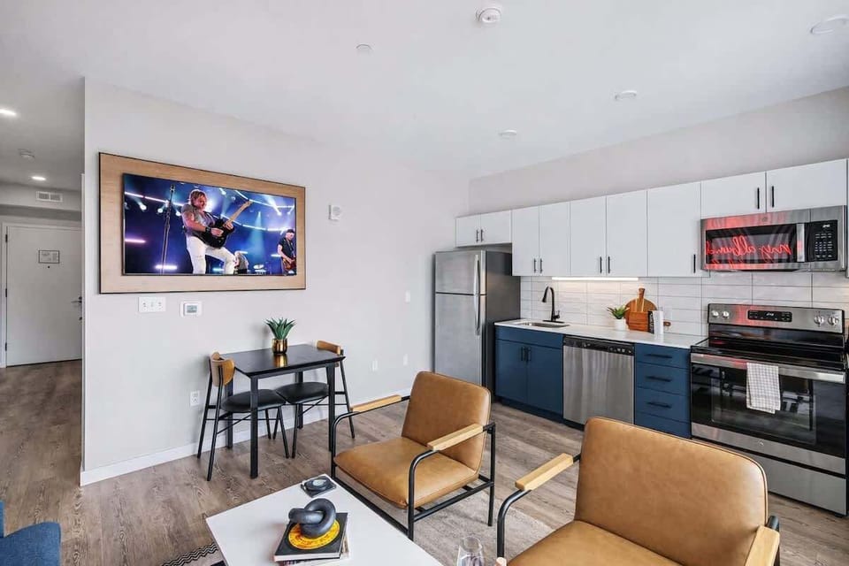 Bright open floor living space featuring a smart flat-screen TV and designer furnishings. Connects to the dining area and kitchen.