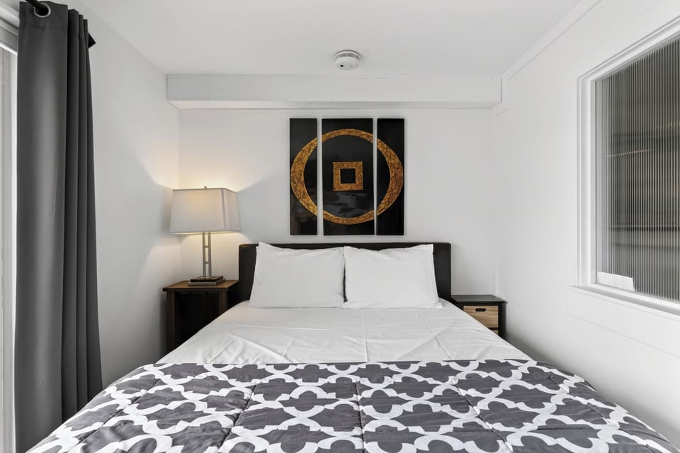 Comfortable queen-sized bed featuring geometric wall art.