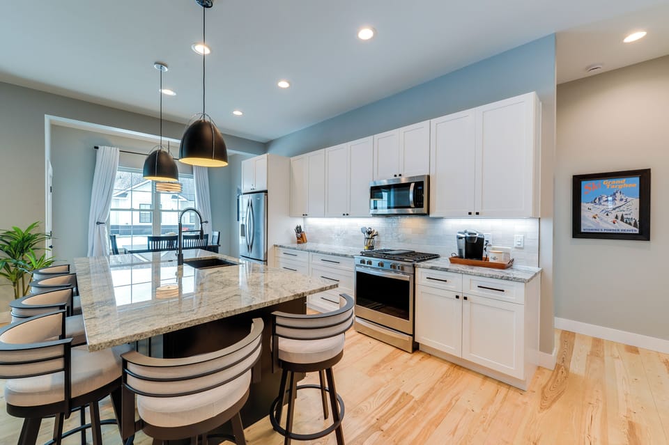 The fully equipped kitchen features sleek cabinetry, stainless steel appliances, and a large island perfect for gathering.