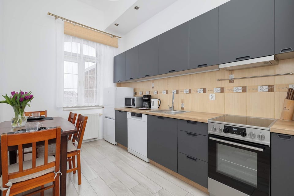 Modern Kitchen with Gray Cabinets – Fully equipped kitchen with gray cabinetry, wooden backsplash, and modern appliances.