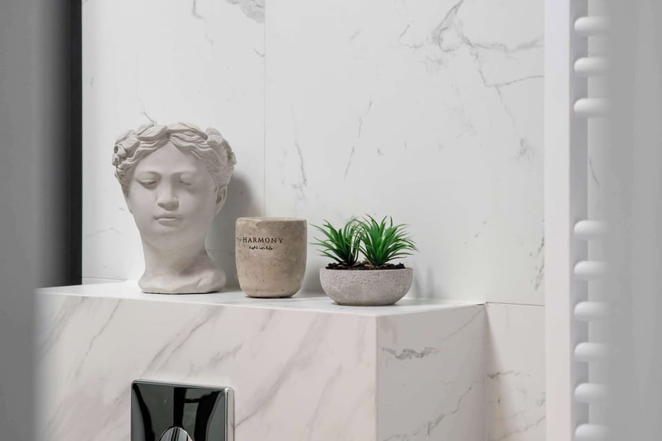 Bathroom decorative detail with plants and marble-style finish.