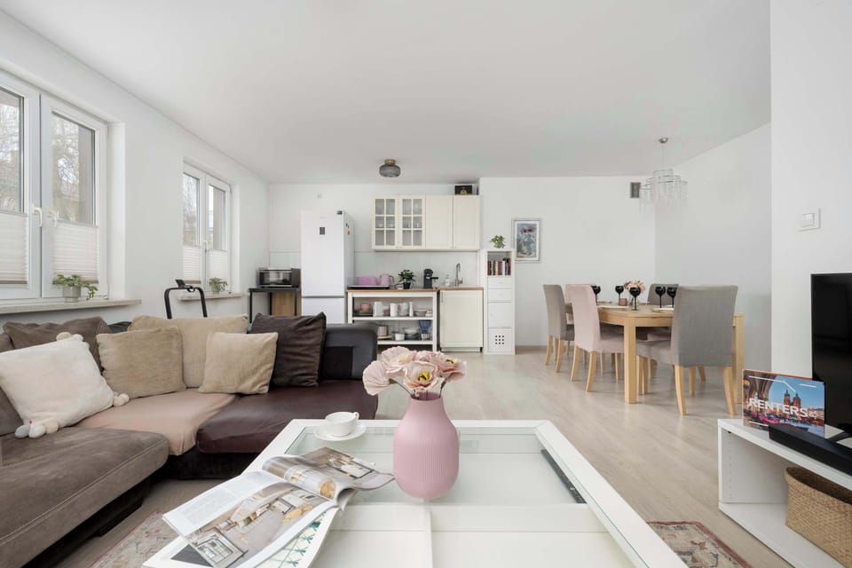 A living room perspective with a sofa, coffee table, and TV. The décor is simple and modern. Natural light brightens the space.