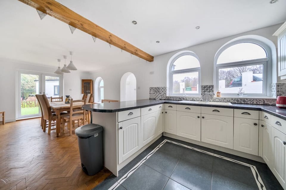 Open-plan kitchen with cream units, arched windows, and adjoining dining area.