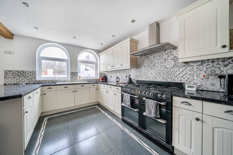 Spacious kitchen with extensive worktops, tiled splashback, and range-style cooker.