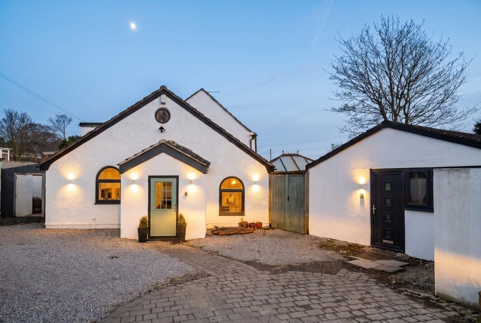 Warm exterior lighting welcomes you home across the courtyard at dusk.