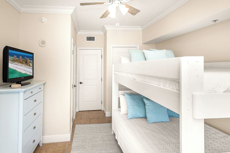 Your kids will love this cozy bunk room with built-in beds, soft blue accents, and entertainment ready for movie nights.