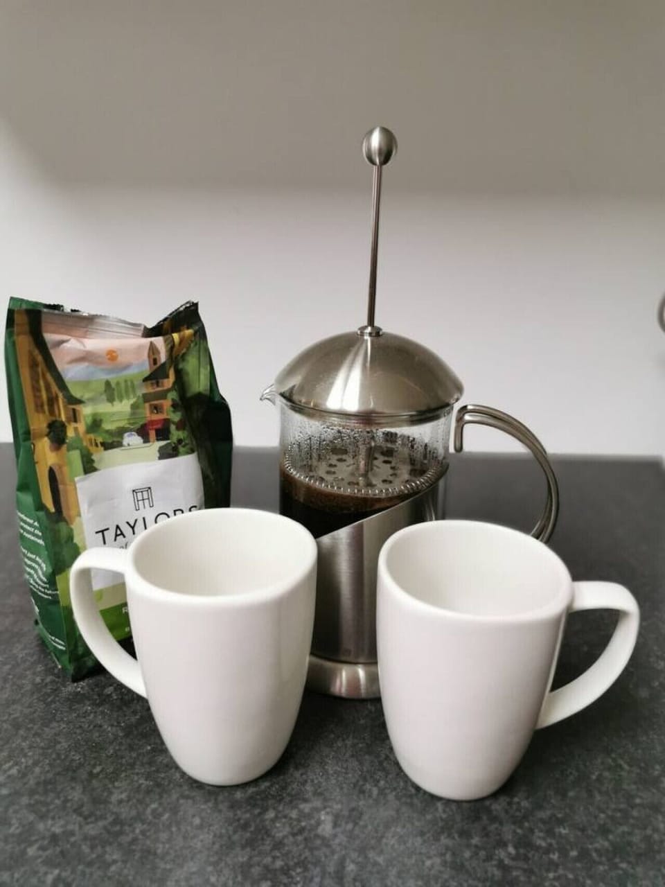 Set up a coffee break with a cafetière and two mugs on the worktop.