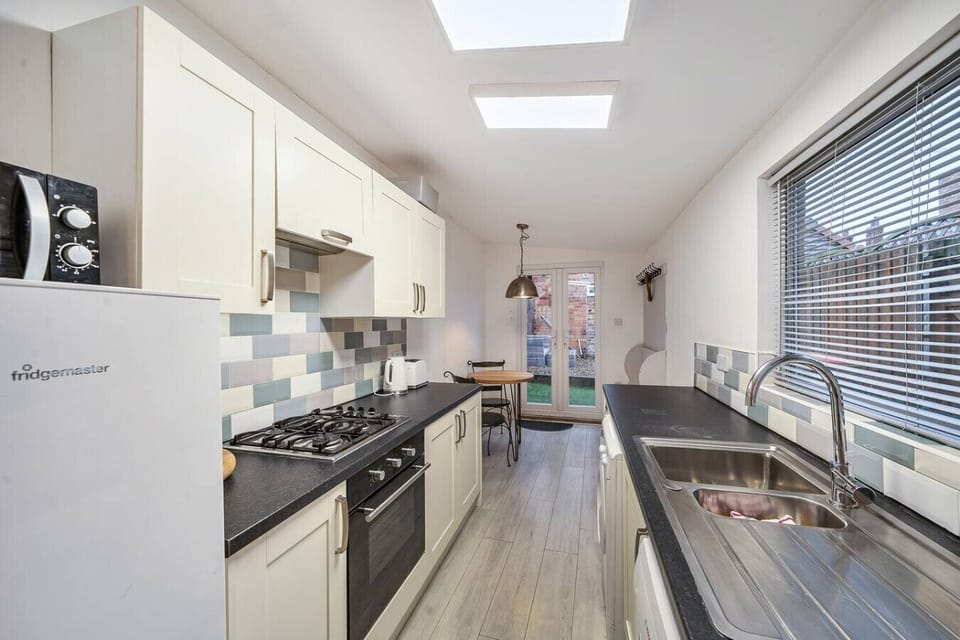 Long galley kitchen with skylights, fitted units, and double doors at the far end.