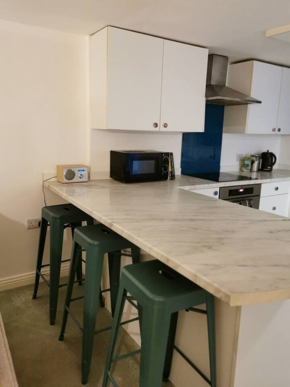 Breakfast bar with four stools beside the kitchen worktop and wall units.