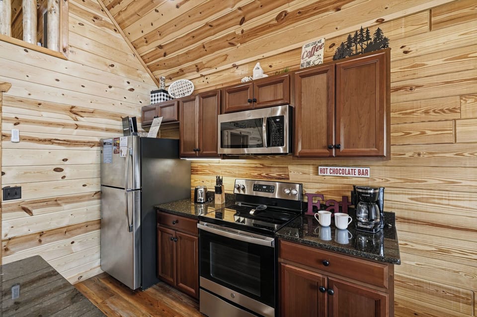 Your cabin kitchen blends rustic charm with modern convenience, featuring stainless appliances, rich wood cabinetry, and a cozy hot chocolate bar ready for mountain mornings.