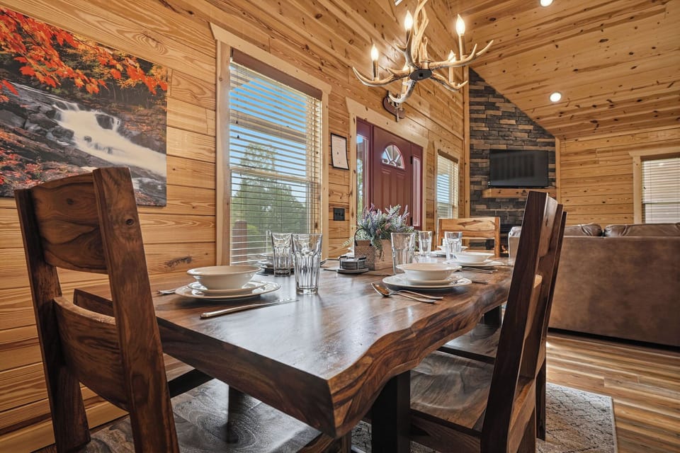 Step inside your cozy cabin where rustic charm meets modern comfort. Natural pine walls and warm lighting welcome you to gather around a beautifully set table, perfect for creating memorable moments together.