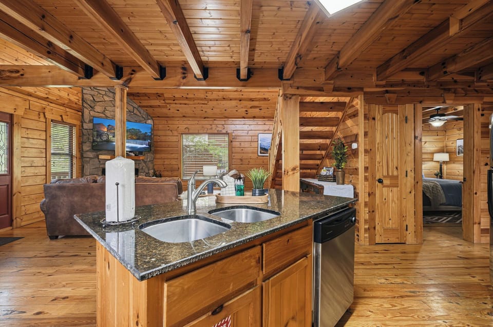 Your rustic kitchen island invites culinary adventures with granite countertops and stainless appliances surrounded by warm wood beams overhead.