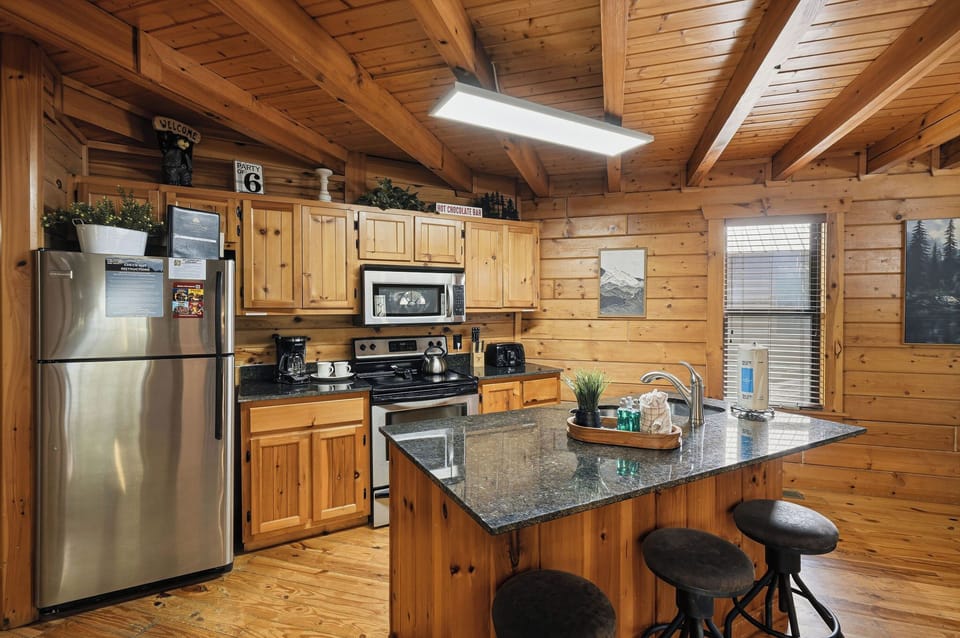 Your cozy cabin kitchen invites you to cook with warm wood beams overhead and granite counters perfect for morning coffee prep.