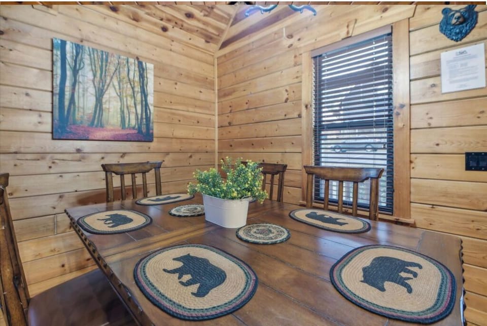 Gather around your rustic dining table adorned with charming bear-themed placemats, where warm cabin walls create the perfect mountain retreat atmosphere.
