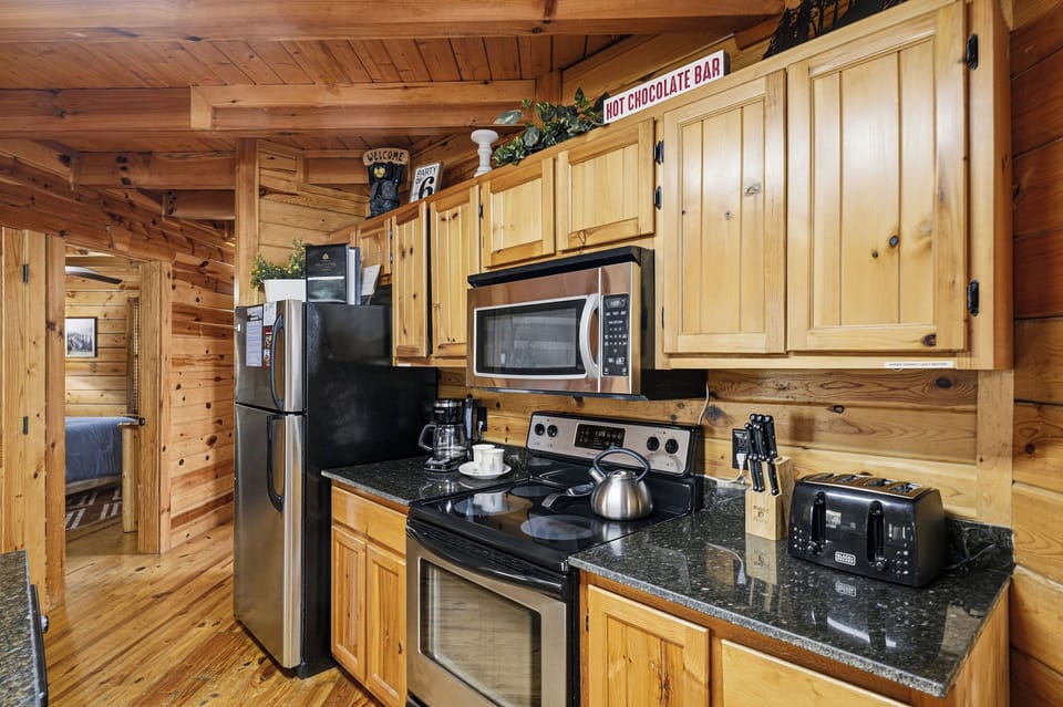 Cook your favorite meals in this fully equipped rustic kitchen with granite counters, modern appliances, and charming wooden cabinetry throughout.