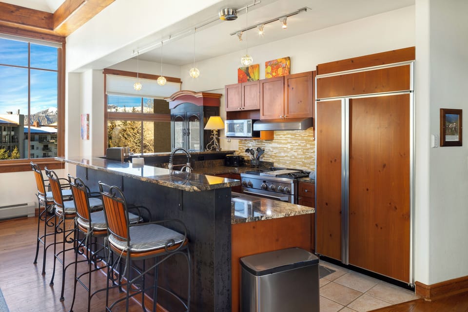 Cook together in your fully equipped gourmet kitchen featuring granite countertops, stainless appliances, and mountain views through oversized windows.