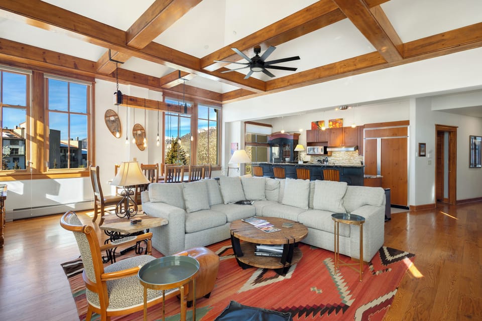 Unwind in this stunning open-concept living space with soaring wood beam ceilings and mountain views through expansive windows.