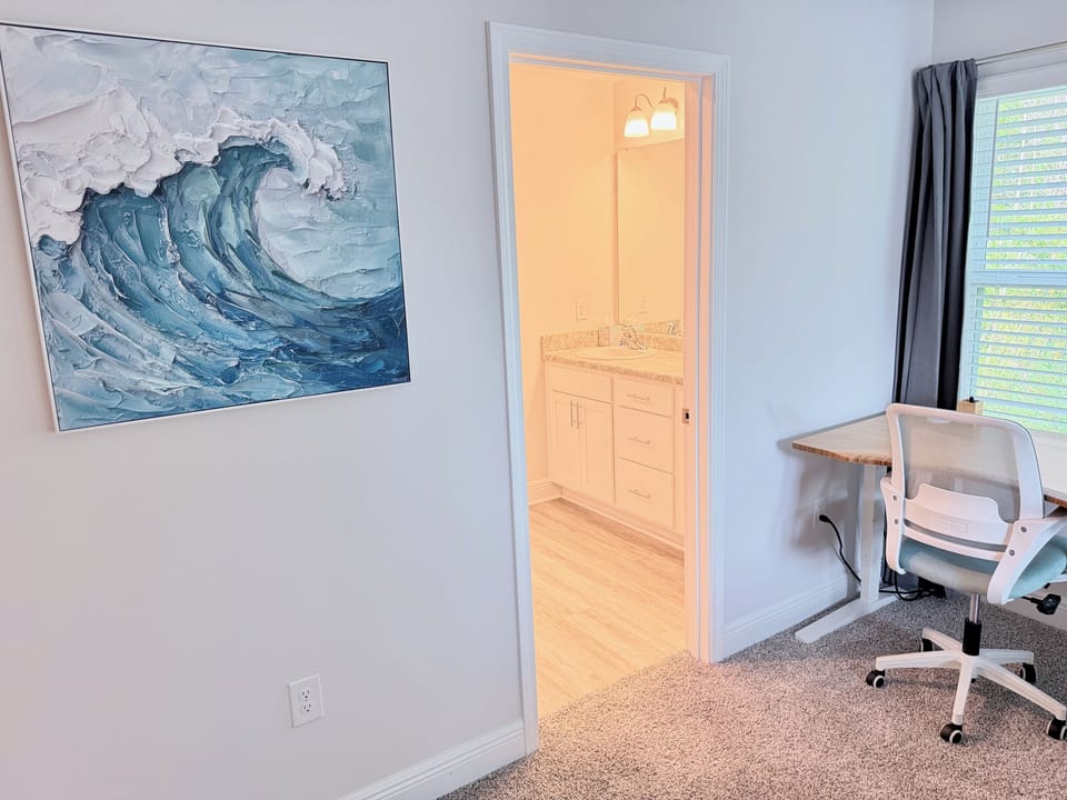Bright room with workspace, coastal art, and private bath access