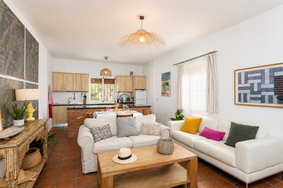 Open-plan living room with sofas, dining area, kitchen, ornamental fireplace, A/C, WiFi internet, and satellite TV