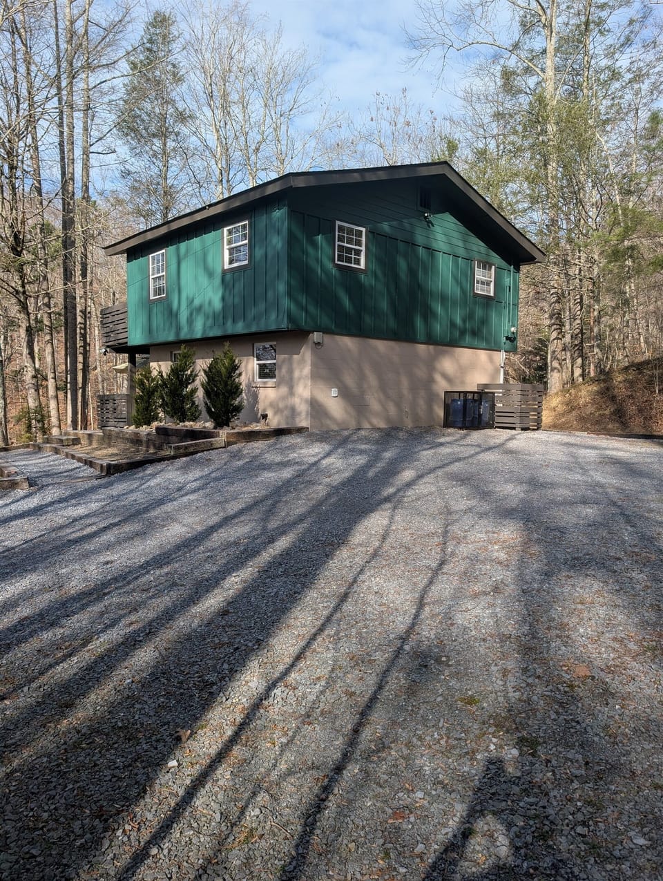 View of parking area with paved driveway and back of cabin with bear proof trash bins