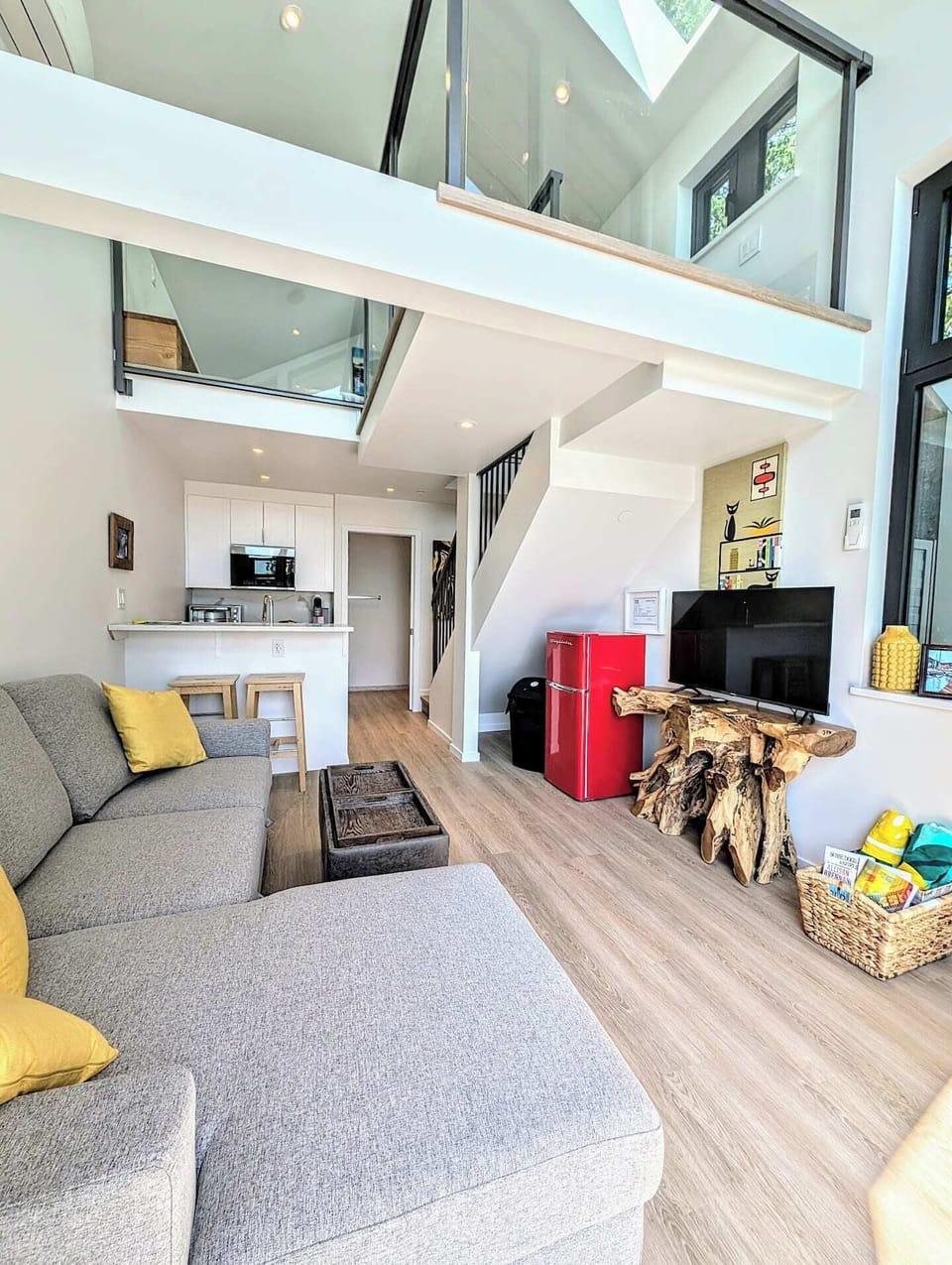 Bright ocean-view living space with sectional seating, TV, fridge/freezer, and direct access to the private patio. Enjoy sunsets, sea air, storm watching, and passing ferries.