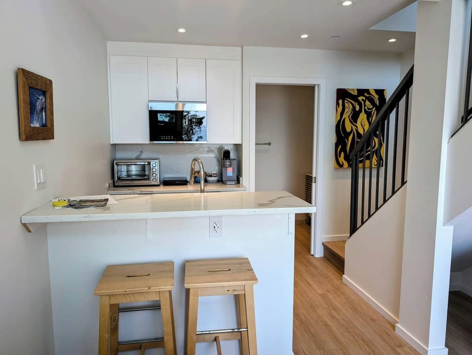 Modern kitchenette with induction cooktop, microwave, toaster oven, coffee maker, and full dishware—perfect for easy meals and morning coffee.