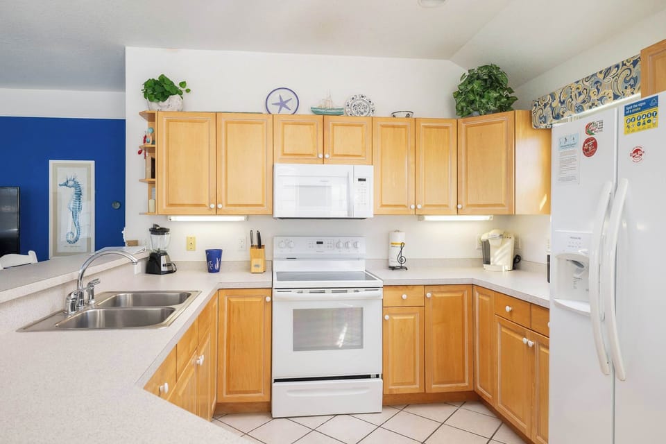 Fully Equipped Kitchen w/ Breakfast Bar, White Appliances, Wood Cabinets, Bar Seating, and Natural Light