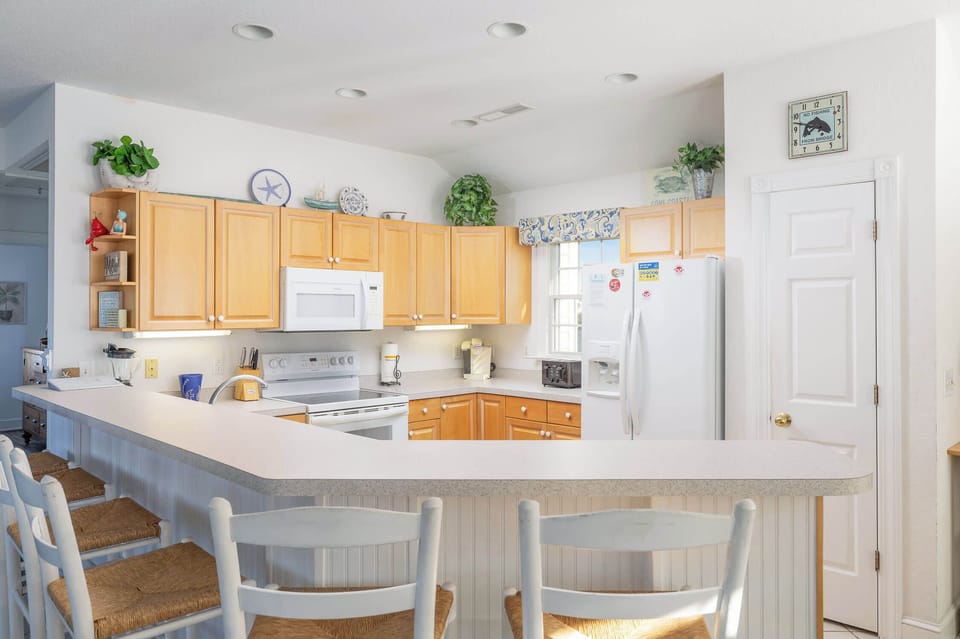 Bright Kitchen w/ Breakfast Bar, White Appliances, Wood Cabinets, Bar Seating, and Natural Light