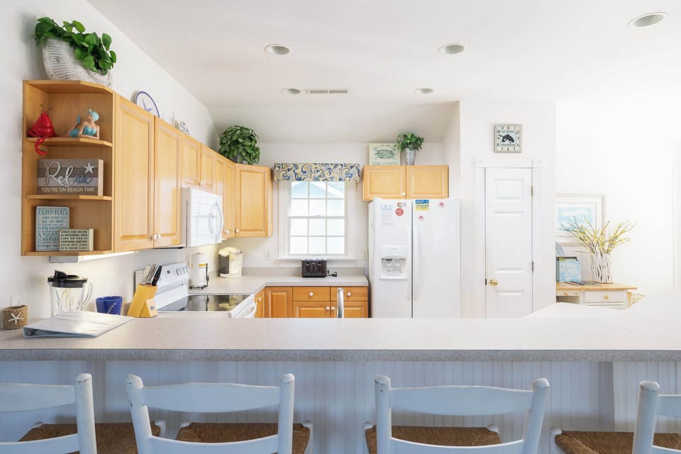 Fully Equipped Kitchen w/ Breakfast Bar, White Appliances, Wood Cabinets, Bar Seating, and Natural Light