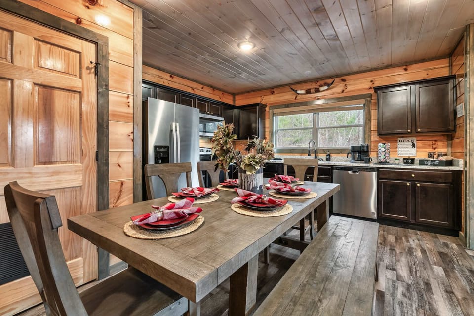 Enjoy group dinners at a large wooden farmhouse-style table with a mix of chairs and bench seating.