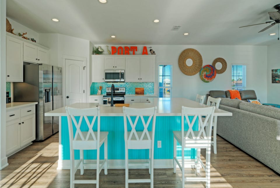 Spacious coastal kitchen with a large island, bar seating, and bright open layout—ideal for casual meals and gathering with the whole group.