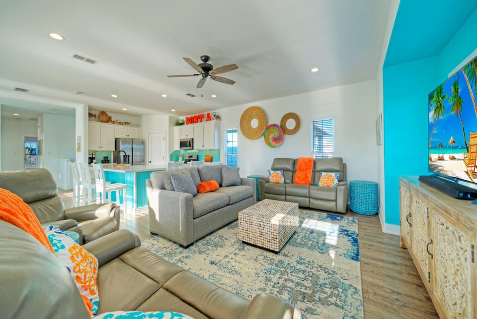 Bright, coastal-style living room with sleeper sofa, smart TV, and easy flow to the dining area—perfect for relaxing after a day at the beach.