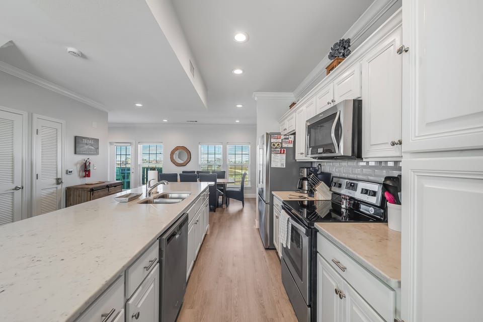 Your spacious kitchen features gleaming countertops, stainless steel appliances, and abundant cabinet space for preparing memorable meals during your stay.