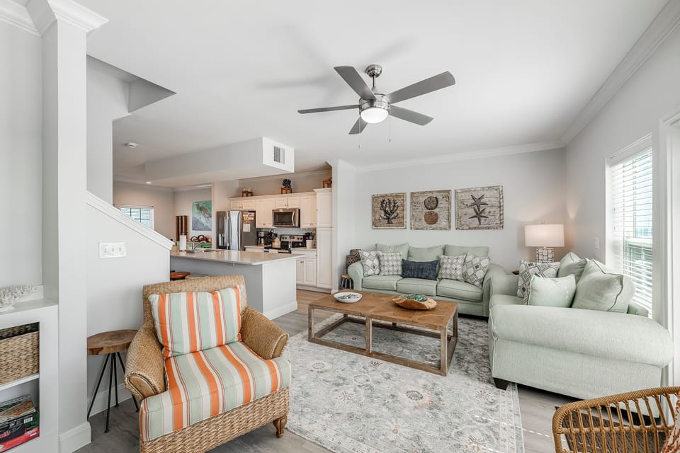 Unwind in your bright, coastal-inspired living room where soft sea-foam furniture and coastal artwork create the perfect retreat after beach days.