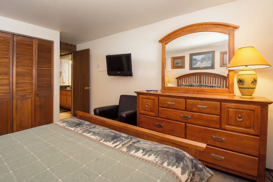 Your warm bedroom features rich wood furnishings, a cozy leather chair, and thoughtful touches that create your perfect retreat.