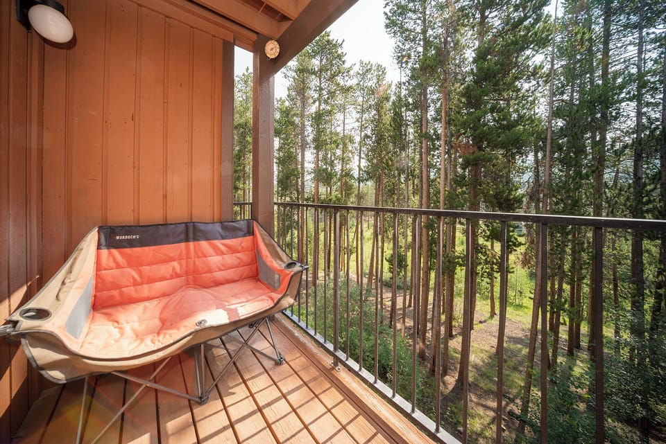 Relax on your private balcony with a cozy outdoor loveseat, surrounded by towering forest views that create the perfect woodland retreat.