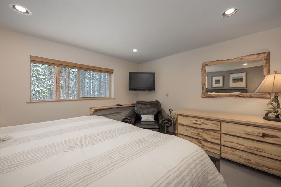 Drift off in your cozy bedroom with natural wood furnishings and peaceful forest views through the window.