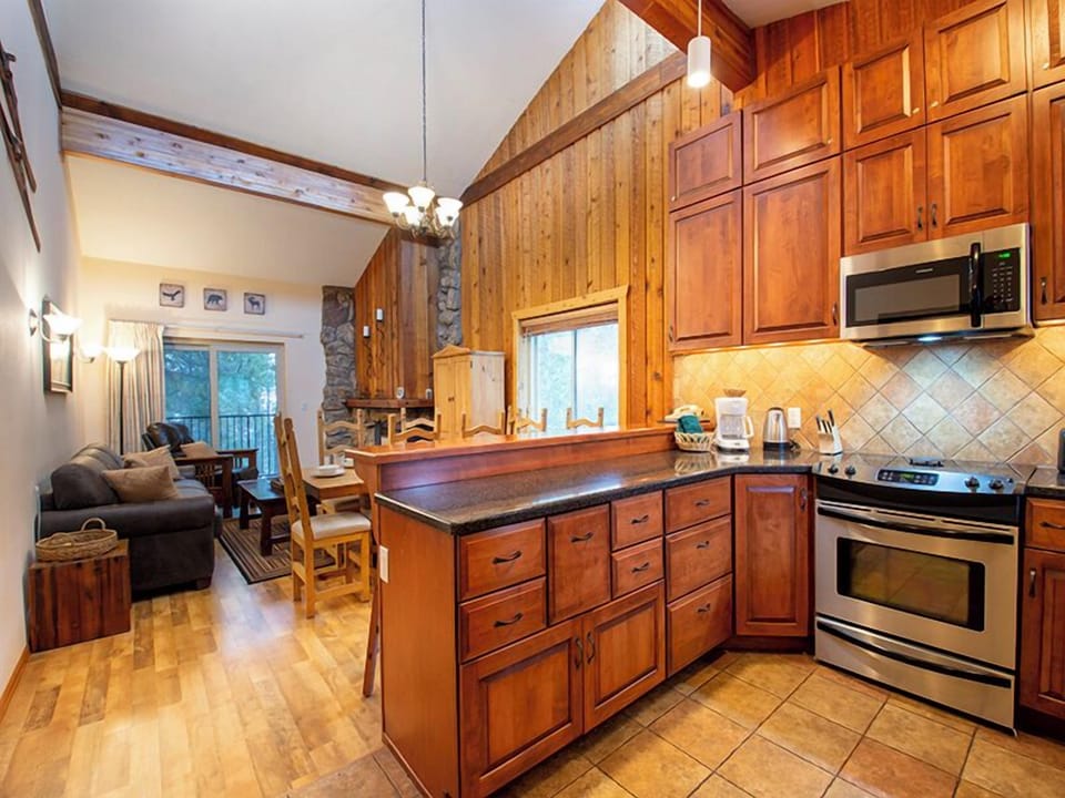 Your fully equipped kitchen features warm wood cabinetry and modern appliances, perfect for preparing meals while staying connected to the cozy living area.