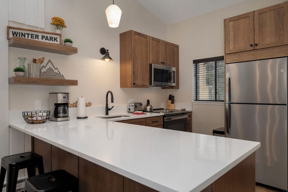 Your modern kitchen features gleaming white countertops, warm wood cabinets, and stainless steel appliances perfect for preparing memorable meals during your stay.