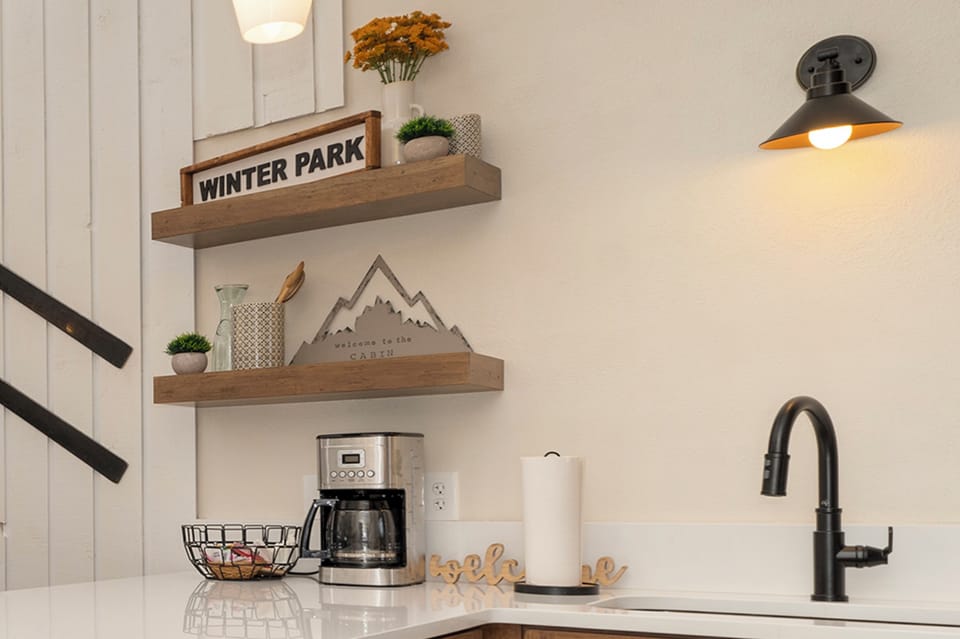 Start your mornings with freshly brewed coffee in this stylish kitchen corner, complete with charming mountain-themed decor and rustic floating shelves.