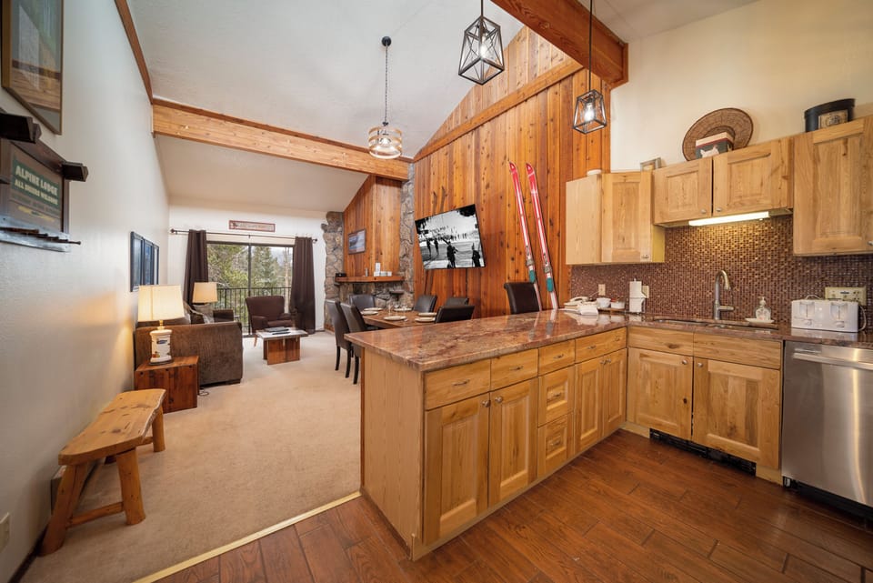 Warm wood cabinets and rustic beams create your perfect mountain retreat kitchen, flowing seamlessly into a cozy living space.