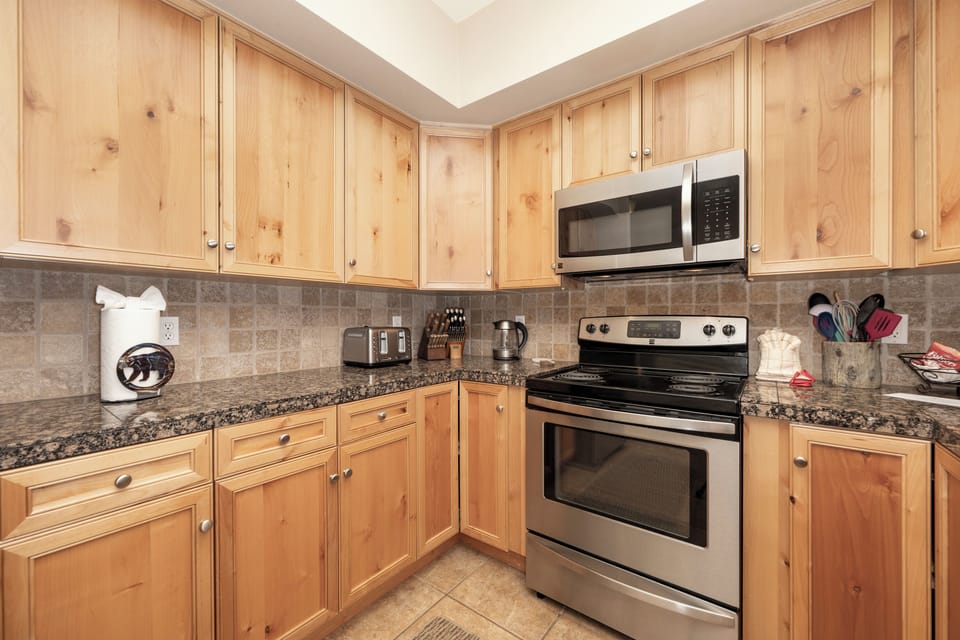 Your fully equipped kitchen features warm wood cabinets, granite counters, and stainless appliances—perfect for preparing meals during your stay.